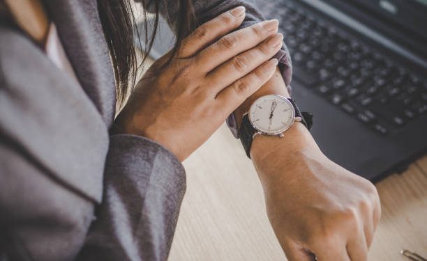 businesswoman checking the time on watch at her office waiting for someone coming late